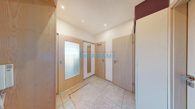 Két szobás lakás előszobája járólappal, világos ajtókkal és tükörrel.