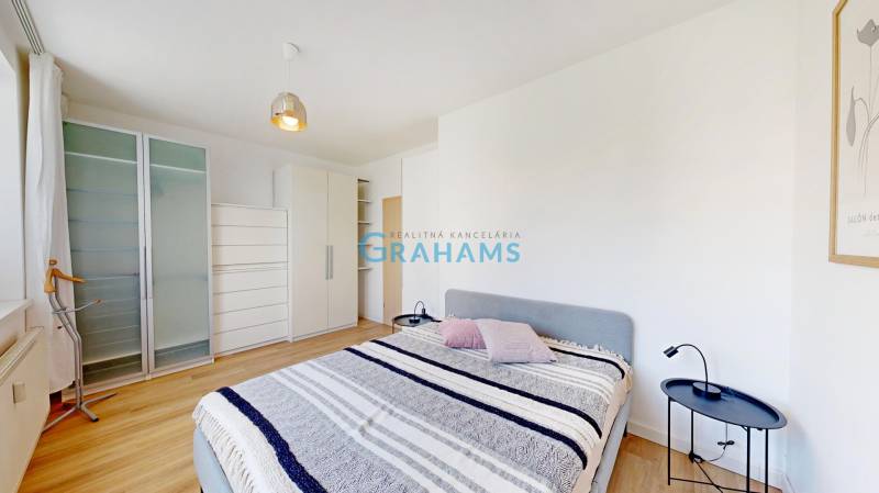 Hálószoba egy kétszobás lakásban ággyal, szekrényekkel és fa dekorációjú padlóval.