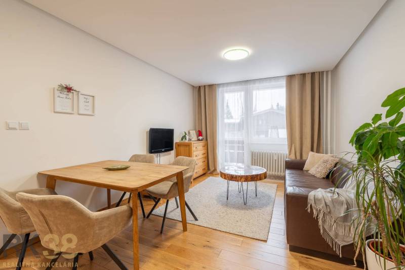 Nappali egy nyaraló apartmanban, hangulatos kanapéval és fa dekorációjú padlóval.