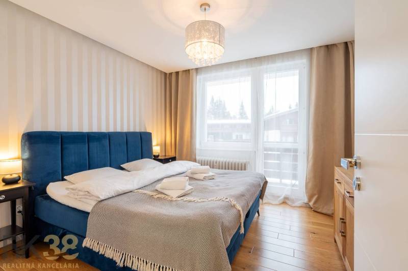 Nyaraló apartman hálószobája kényelmes ággyal és fa dekorációjú padlóval.