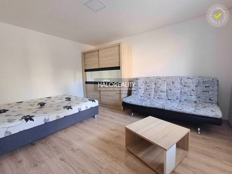 1 szobás lakás belső tere ággyal, kanapéval és fa dekorációjú padlóval.