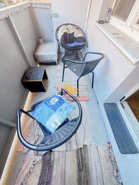 Erkély bútorokkal a kétszobás lakásban, a dekoratív székek és szőnyeg otthonosságot kölcsönöznek.