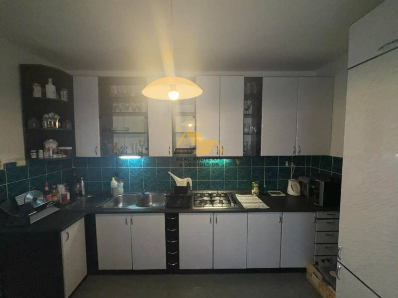 Konyha egy kétszobás lakásban fekete munkalappal és fehér szekrényekkel.