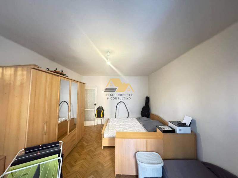 Hálószoba egy kétszobás lakásban fa mintázatú padlóval és tárolóhellyel.