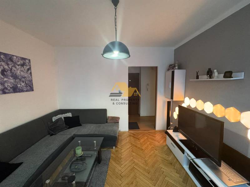 Nappali fa mintás padlóval és világítással egy kétszobás lakásban.