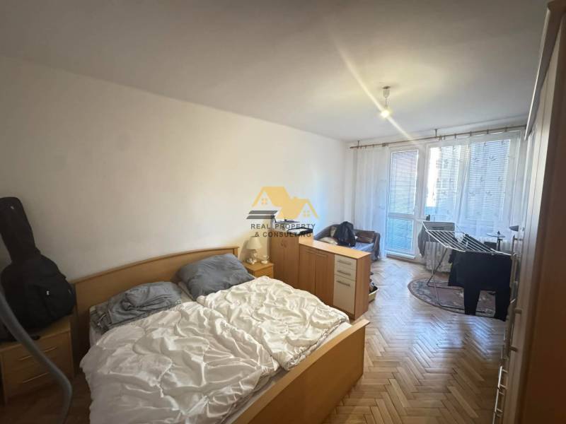 Hálószoba egy kétszobás lakásban bútor garnitúrával és fa dekor padlóval.