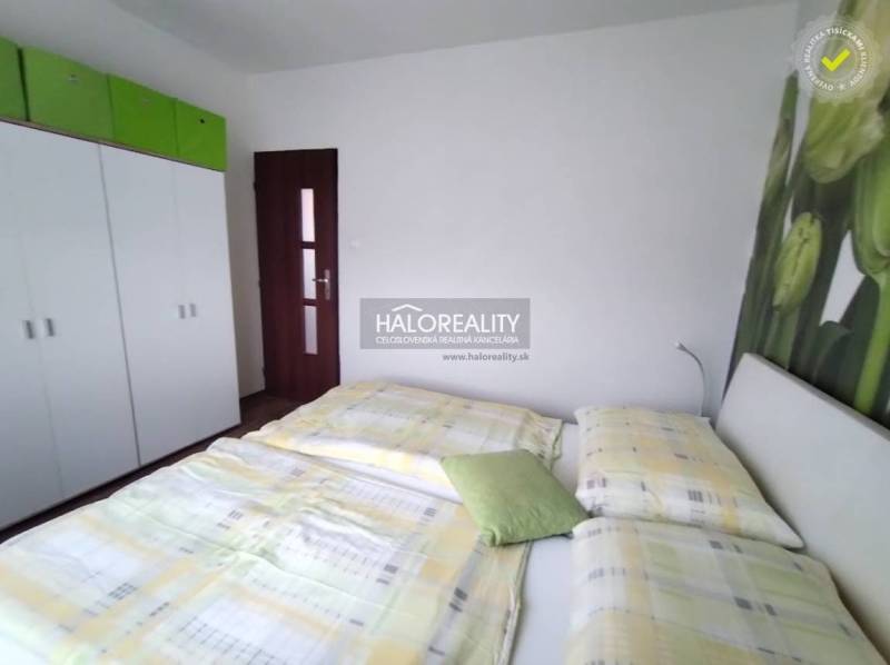 Hálószoba egy 4 szobás lakásban ággyal, szekrénnyel és virágos dekoratív fallal.