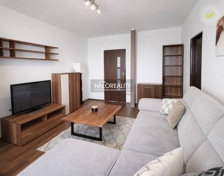 Nappali szoba fa hatású padlóval, kanapéval és televízióval egy négy szobás lakásban.