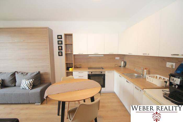 Kompakt konyha és nappali rész fa dekor padlóval egy egyszobás lakásban.