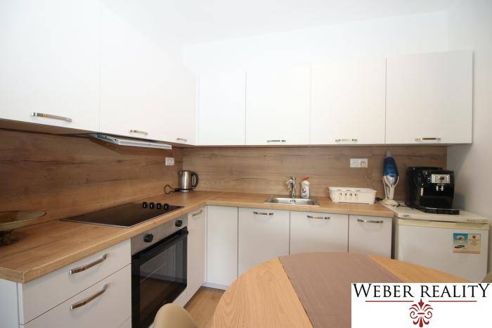 Beépített készülékekkel és fa dekorációval ellátott konyha egy egyszobás lakásban.