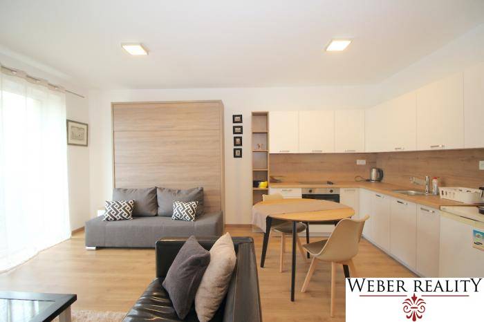 Nappali szoba konyhával egy egyszobás lakásban, fa dekoros padlóval.