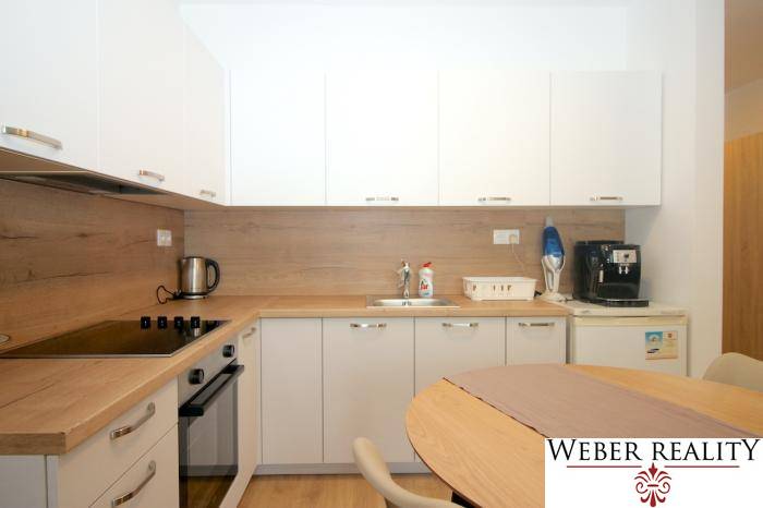 Fehér konyha fa dekorációval az egyszobás lakásban, háztartási gépekkel.