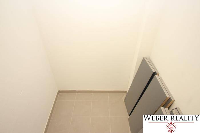 Kis tárolóhely egy egyszobás lakásban csempével és fehér falakkal.