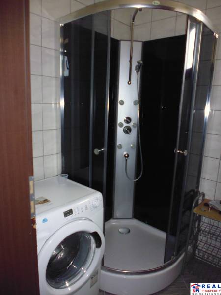 Fürdőszoba egy háromszobás lakásban mosógéppel és zuhanyzóval.