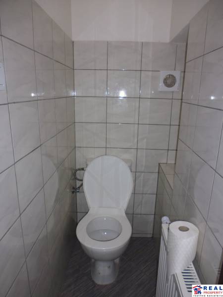 Háromszobás lakás WC-je csempével és szellőzőnyílással.