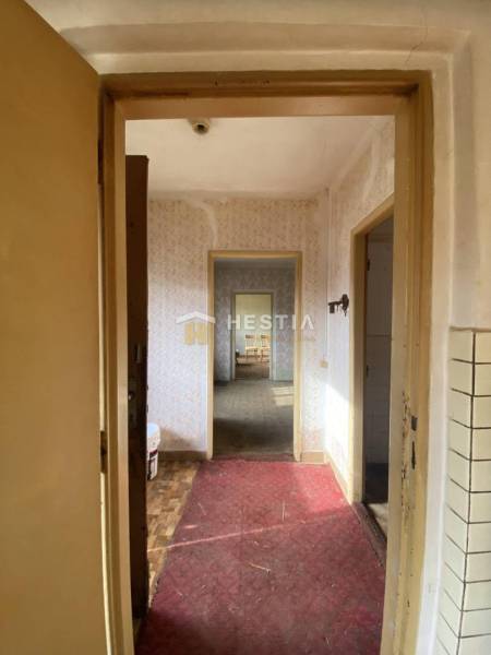 Folyosó egy családi házban fa dekor padlóval és egyszerű falakkal.