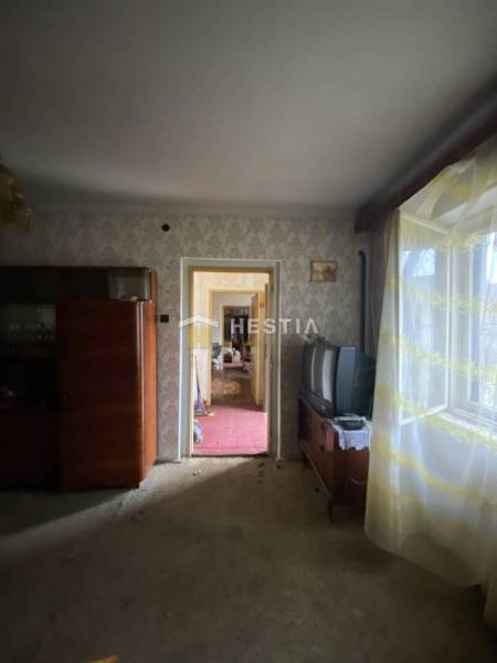 Egy szoba családi házban retro bútorokkal, régi televízió, ablak virágos függönyökkel.