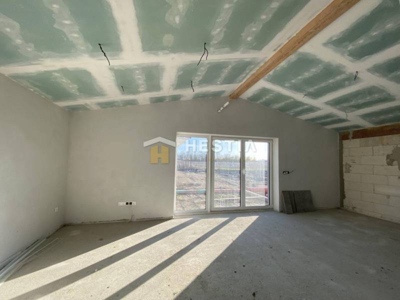 Családi ház befejezetlen szobája ablakokkal és kilátással a kertre.