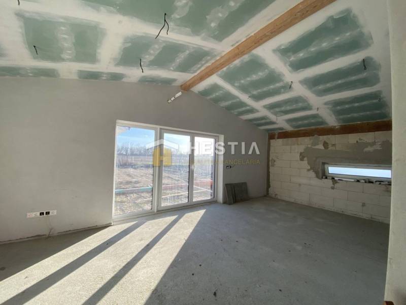 Családi ház belső tere betonpadlóval és nagy ablakkal.