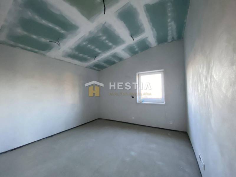 Szoba egy családi házban fehér falakkal és ablakkal.