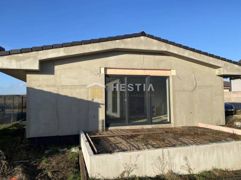 Családi ház Sekule városában, befejezetlen terasszal és nagy üvegajtókkal.