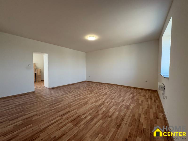 Szoba egy családi házban fa dekoros padlóval és fehér falakkal.