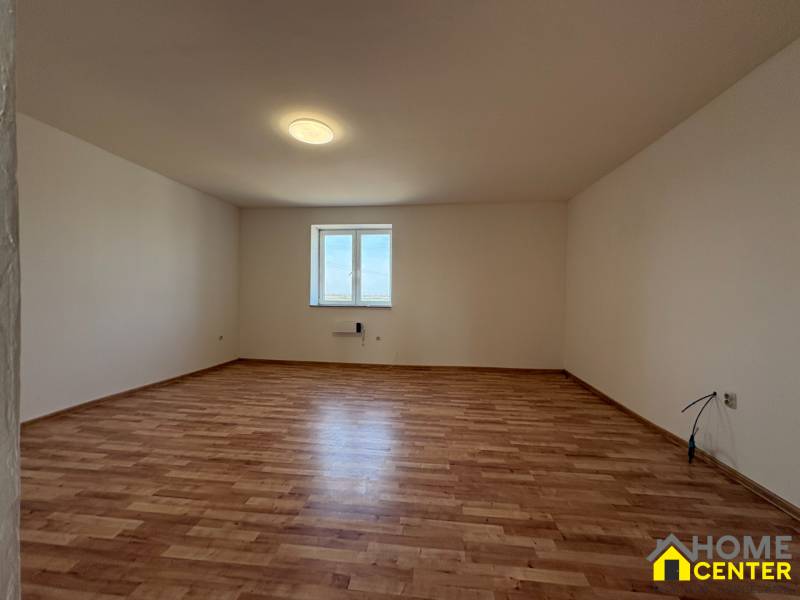 Tágas szoba ablakkal és fa dekorációjú padlóval egy családi házban.