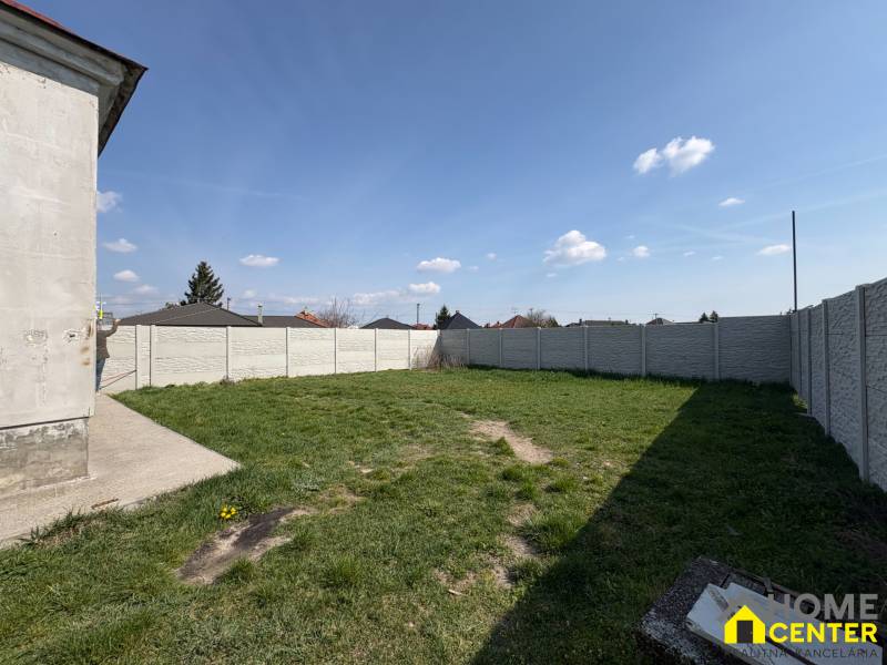 Családi ház kertje Nemesócsán, kerítéssel körülvéve, füves felület.