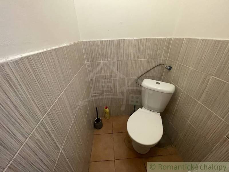 Családi házban lévő WC kerámia padlóval és csempékkel.