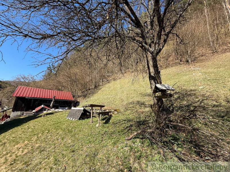 Házikó Moštenica közelében, fákkal és füves dombokkal körülvéve, napsütéses időben.