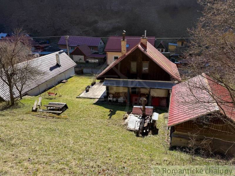 Házikó Moštenicában, gyep és fák veszik körül.