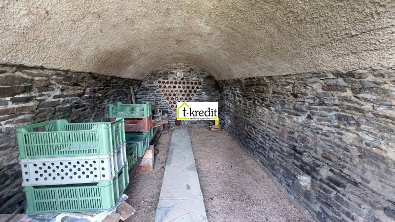 Kőpince polcokkal és műanyag ládákkal a szőlőskertben.