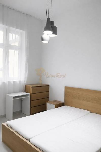 Hálószoba fából készült bútorokkal és függő világítással egy kétszobás lakásban.