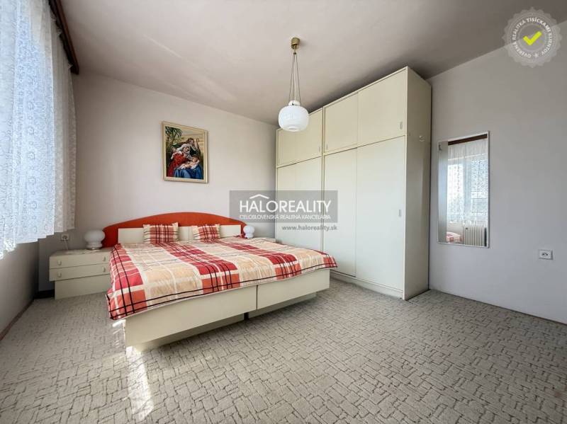 Hálószoba családi házban nagy szekrénnyel, ággyal és képpel a falon.