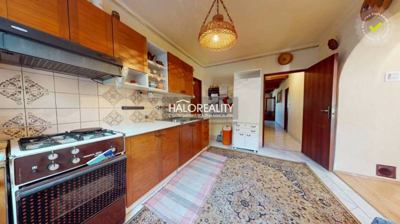 Konyha családi házban szőnyeggel, gáztűzhellyel és fa szekrényekkel.