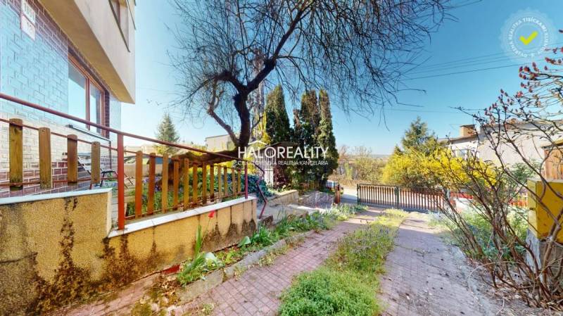 Családi ház Rimaszombatban udvarral, fákkal és kövezett járdával.