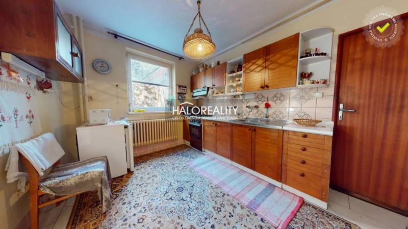 Konyha családi házban fa szekrényekkel, szőnyeggel és függő lámpával.