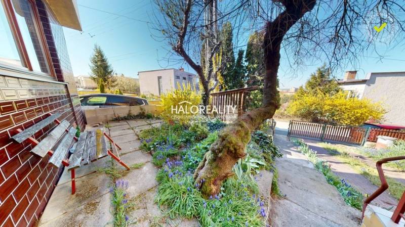 A rimavszombati családi ház előtt van egy kert, egy pad és egy fa.