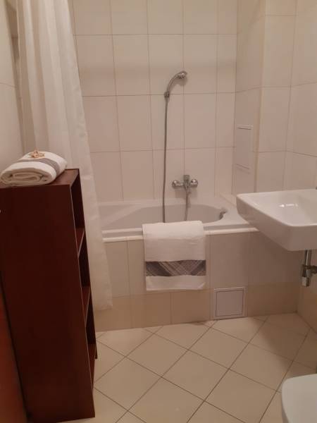 Fürdőszoba egy háromszobás lakásban káddal és fehér csempékkel.