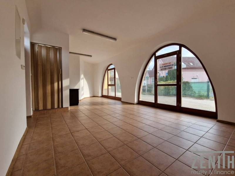 Üzlethelyiségek belső tere nagy boltíves ablakokkal, csempével és faajtókkal.