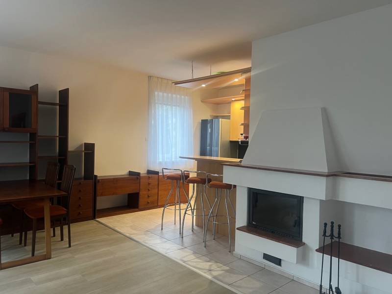 Konyha és nappali kandallóval és bárpulttal, fa hatású padlóval.