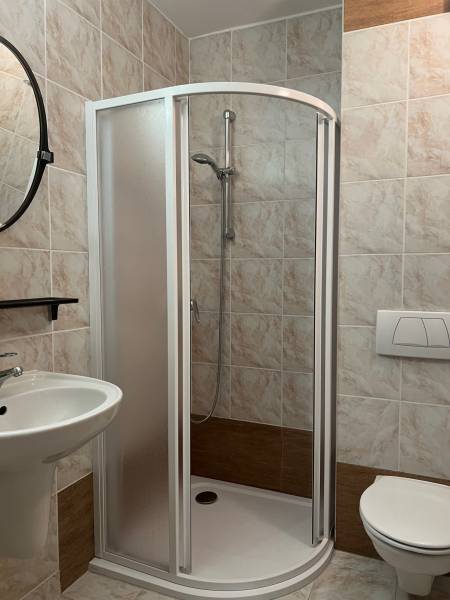 Fürdőszoba WC-vel, zuhanyzóval és mosdóval egy családi házban, csempével burkolva.