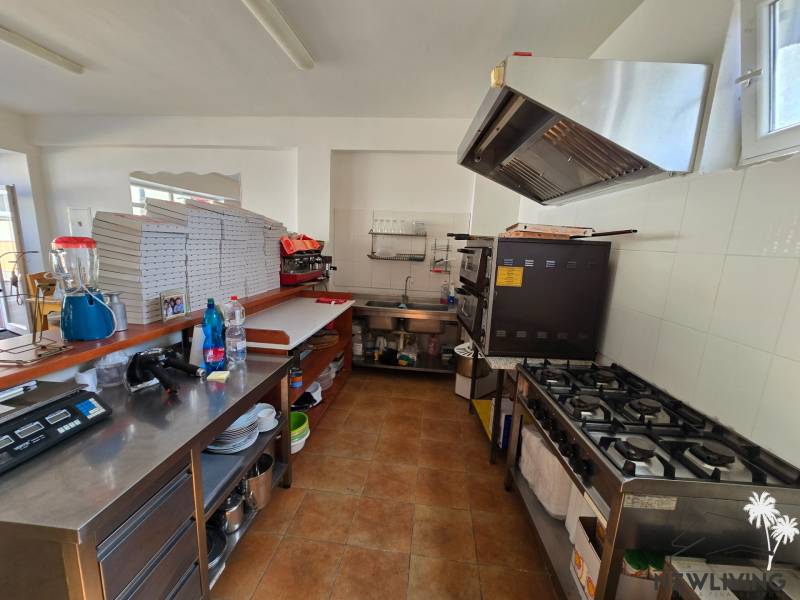 Professzionális készülékekkel és készletekkel felszerelt gasztronómiai helyiség konyhája fa dekor padlón.