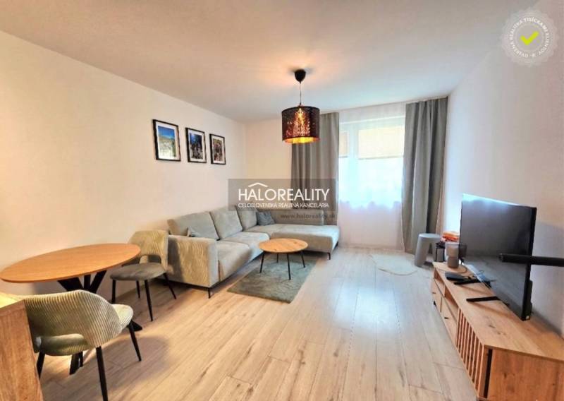 Világos nappali egy kétszobás lakásban kényelmes kanapéval és fa dekorációjú padlóval.