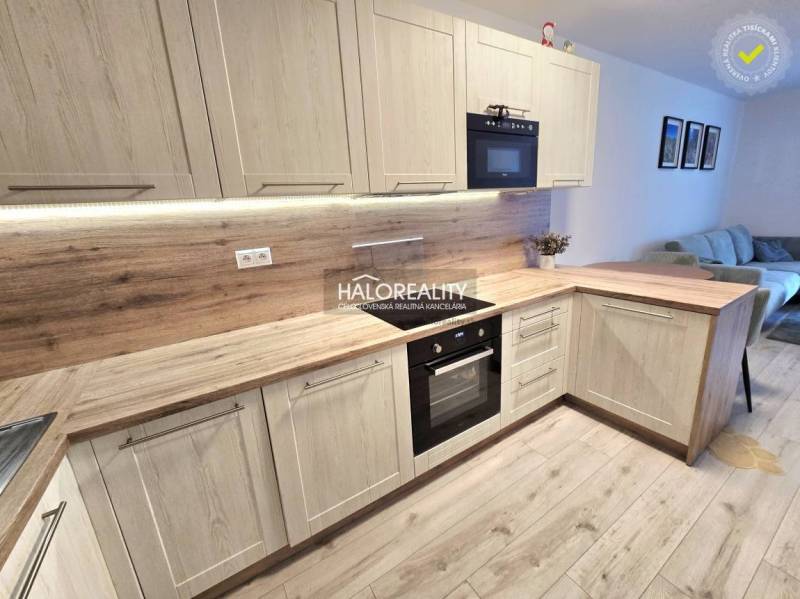 Konyha fa dekor padlóval egy kétszobás lakásban, világos fa szekrényekkel és beépített készülékekkel.