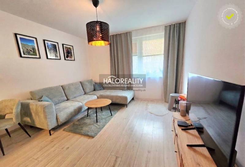 Nappali egy kétszobás lakásban, fa dekorációjú padlóval és kényelmes ülőgarnitúrával.