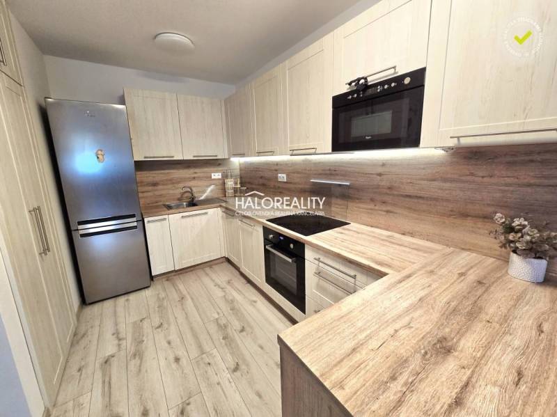 Konyha egy kétszobás lakásban, fa dekoros padlóval és világos bútorokkal.