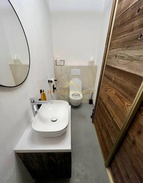 Fürdőszoba egy háromszobás lakásban tükörrel, mosdóval és modern dekorációval.