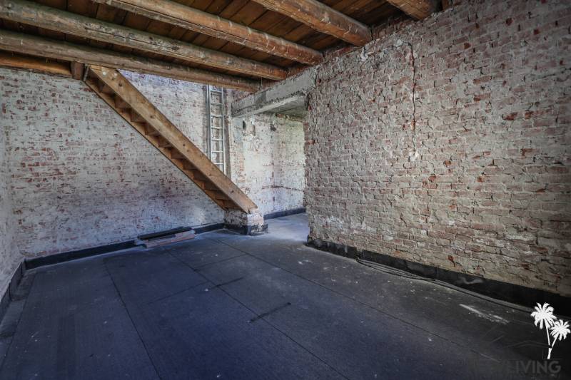 Téglafalak és lépcsők a családi ház tetőterében, fa dekoros padlóval.