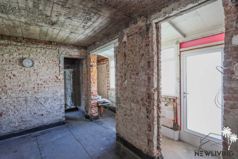 Családi ház befejezetlen téglafalakkal és fehér ajtókkal, betonpadlóval.